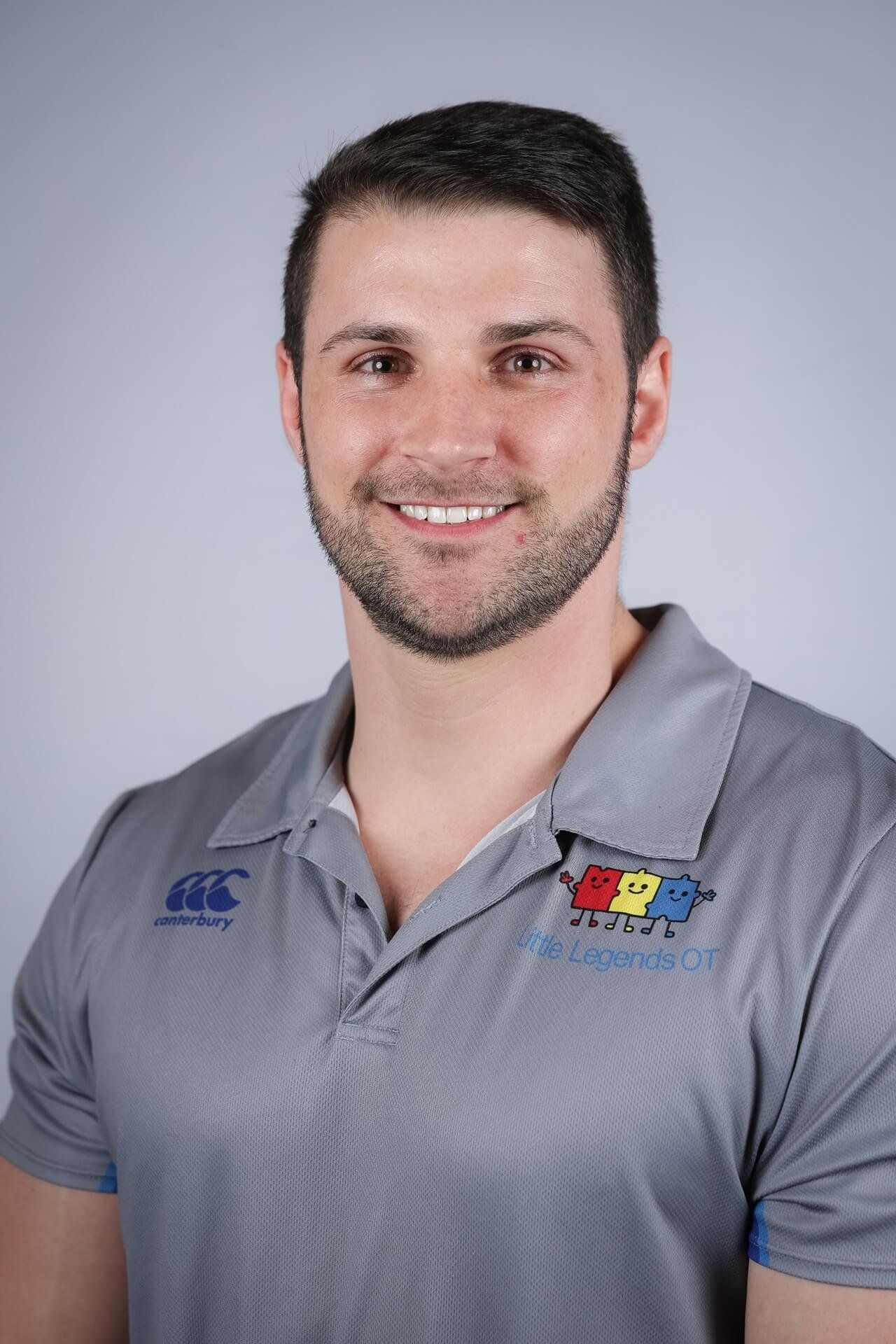 Luke Casey, Principal Occupational Therapist and Director of Little Legends OT, in a grey Little Legends polo shirt.